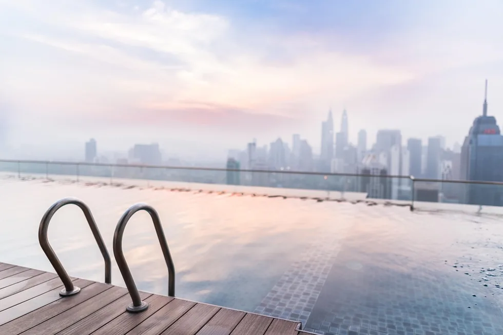 A rooftop infinity pool overlooking a hazy city skyline