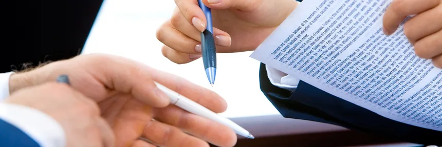 Two people reviewing printed documents with pens in hand