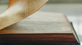 An old open book with a page being turned
